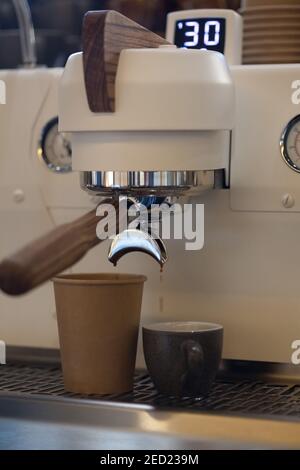 Nahaufnahme der modernen professionellen Espressomaschine im Café mit Kaffeeausguss in Take Away Pappbecher, niemand Stockfoto