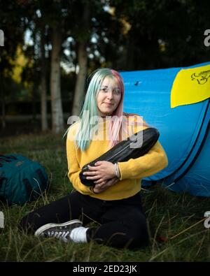 Eine Aktivistin von Animal Rebellion sitzt vor seinem Zelt und kadelt eine große Zucchini auf einem Campingplatz im Brockwell Park, London, 31. August 2020 Stockfoto