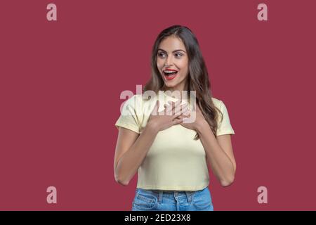Überraschte Frau, die die Hände an ihre Brust hält Stockfoto
