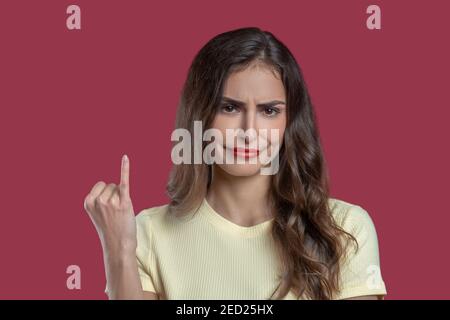 Frau mit bedauernswerter Grimasse, die ihr pinky zeigt Stockfoto