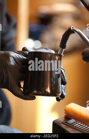 Barista Hände dämpfen Milch für Kaffee in modernen Espressomaschine, Nahaufnahme Stockfoto