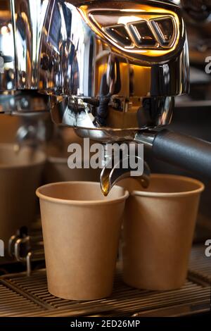 Kaffeegießen aus der professionellen Espressomaschine in die Papiertasse, Nahaufnahme Stockfoto