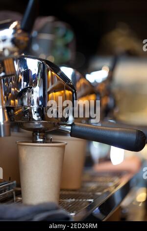 Kaffeegießen aus der professionellen Espressomaschine in die Papiertasse, Nahaufnahme Stockfoto