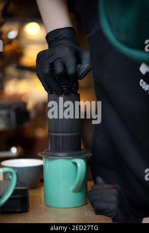 Barista Hände drücken Aeropress in die Tasse, Nahaufnahme der Kaffee brauen Stockfoto