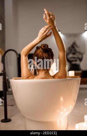 Junge Frau in der schönen Vintage-Bad voller Schaum in der Retro-Badezimmer mit Kerzen dekoriert entspannen. Stockfoto