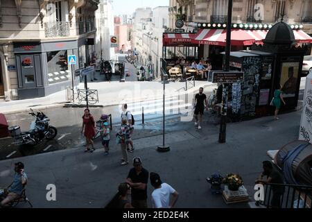 MONTMARTRE, PARIS - 29th. JUNI 2019: Eine geschäftige Pariser Straße in der Rue Lamarck Szene im 18th Arrondissement. Im Café La Refuge sitzen Einheimische in der Sonne. Stockfoto