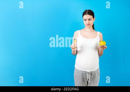 Spritze zur Injektion in die Hand der schwangeren Frau auf farbigem Hintergrund mit Kopierraum. Medizinische Behandlung während der Schwangerschaft Konzept. Stockfoto
