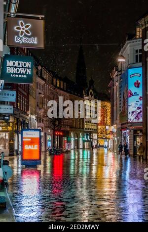 Neonschilder spiegeln sich in nassem Bürgersteig auf verlassene Highstreet Stockfoto