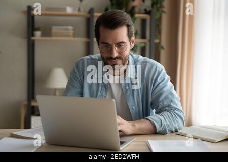 Konzentrierter junger Mann Spezialist tun Remote-Computer Arbeit auf Laptop Stockfoto