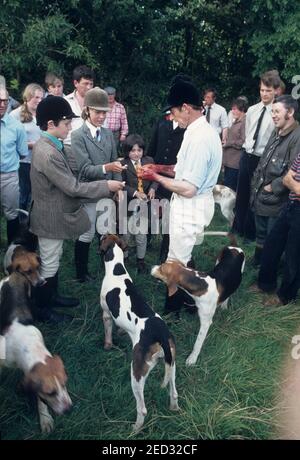 Devon und Somerset Staghounds August 25th 1981. Nach dem Gralloch. Der Hirsch wurde getötet. Der Mageninhalt, der den Hunden gegeben wurde, der Körper für Fleisch weggeschleppt und Souvenirs genommen. Hier verkauft der Huntsman, Dennis Boyles, Zähne, die er vom Hirsch an junge Jagdfans gezogen hat. Dies wurde lange vor dem Jagdgesetz 2004, das diesen Zeitvertreib aus Grausamkeit Verbot, durchgeführt. Stockfoto