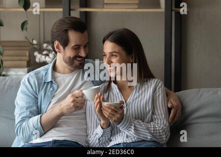 Lächelndes junges Paar in der Liebe sitzt auf der Couch trinken Tee Stockfoto