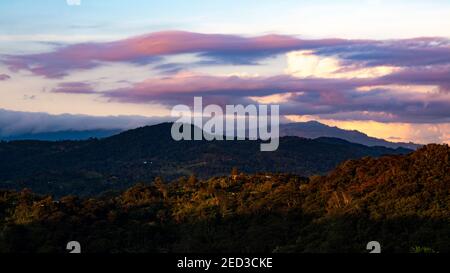 Eine faszinierende Aussicht auf bewaldete Berge unter einem bewölkten Sonnenuntergang Himmel Stockfoto