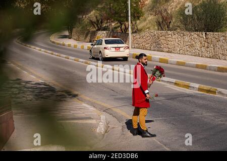 Ein syrischer Flüchtling steht vor einem öffentlichen Park mit einem Blumenstrauß, der am Valentinstag verkauft wird.Ali Khader, ein junger Syrer, der als Straßenhändler für Blumen arbeitet, Nach dem Auftreten der Syrienkrise im Jahr 2012 sein Land verlassen und in den Irak eingewandert, um sich im Duhok Gouvernement in der Region Kurdistan niederzulassen, da er einwanderte, Er verkauft Blumen in der Duhok Dam Gegend, um sich und seine Familie zu unterstützen und ein Lächeln auf die Gesichter der Iraker zu zaubern, die die Blumen von ihm kaufen, zusätzlich zu seiner Arbeit ist er immer noch Abiturienstudent. Stockfoto