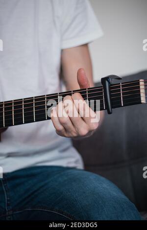 Teil einer Holzgitarre und die Hand eines Sängers, der die Gitarre je nach dem Akkord, den er braucht, hält. Spezieller Griff zum Einstellen des Tons Stockfoto