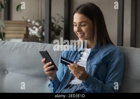 Glückliche junge Frau verwenden Bankkarte, um Waren online zu kaufen Stockfoto