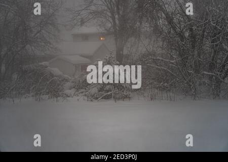 Ein Licht in einem Fenster während eines dunklen Abendwinters Schneesturm Stockfoto