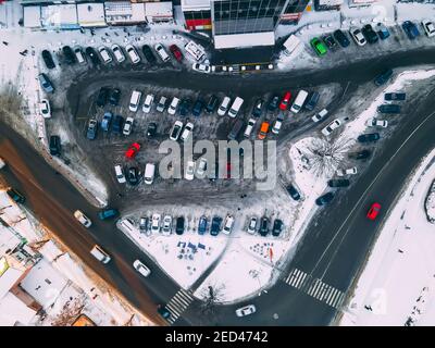 Top down Luftaufnahme des kleinen Parkplatzes in der Nähe Supermarkt in der kleinen europäischen Stadt am sonnigen Winterabend, Ukraine, Europa Stockfoto