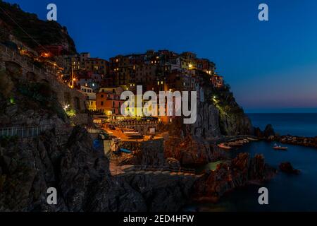 Blick über und über auf eine sehr bunte Nacht in der felsigen italienischen Küste Dorf und historischen Waterfront von Manarola, Cinque Terre, Italien Stockfoto