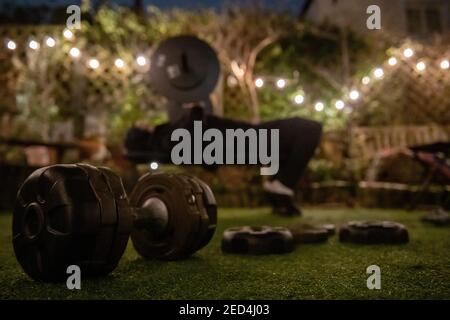 Während der Sperre im Jahr 2021, mit geschlossenen Turnhallen, ein Teenager-Junge trainiert im Garten in einem improvided Fitness-Studio an einem Winterabend Stockfoto