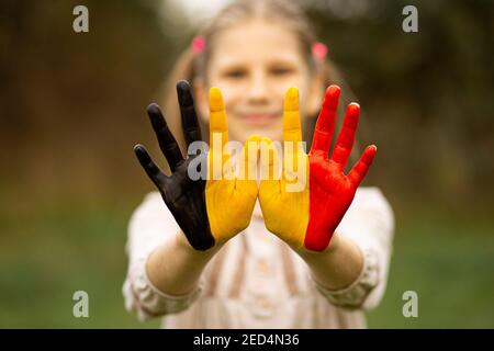 Kind Mädchen zeigen Hände in Belgien Flagge Farben zu Fuß im Freien gemalt, konzentrieren sich auf die Hände Stockfoto