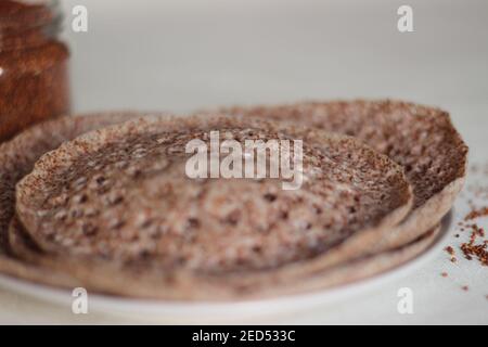 Trichter aus Fingerhirse auch bekannt als Ragi in Indien. Hausgemachte gesunde Lebensmittel auf weißem Hintergrund geschossen. Stockfoto