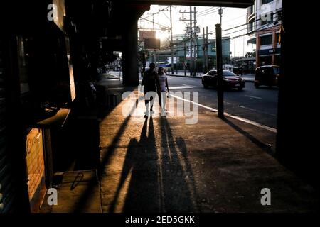 Menschen, die Schutzmasken tragen, gehen während einer COVID-19-Sperre in Manila, Philippinen, an geschlossenen Einrichtungen vorbei. Stockfoto