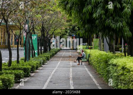 Eine Frau sitzt allein auf einer Bank entlang eines Bürgerwegs während der Coronavirus-Sperre in Bonifacio Global City (BGC) in Metro Manila, Philippinen. Stockfoto