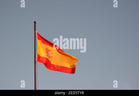 Spanien Flagge weht im Wind mit einem blauen Himmel Im Hintergrund Stockfoto