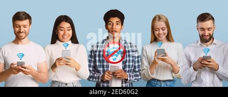 Schwarzer Kerl ohne Internet-Verbindung, steht unter verschiedenen Menschen in Smartphones auf blauem Studio Hintergrund stecken Stockfoto