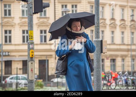 Prag, Tschechische Republik. 02-13-2021. Eine Frau mit Sonnenschirm läuft in der Innenstadt von Prag während eines kalten Wintertages. Stockfoto