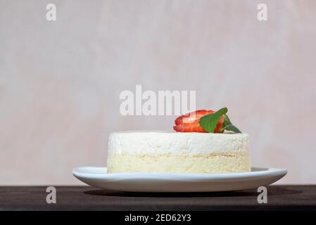 Käsekuchen mit frischen Erdbeeren und Minze auf weißer Schale. Delikates Käsedessert. Stockfoto