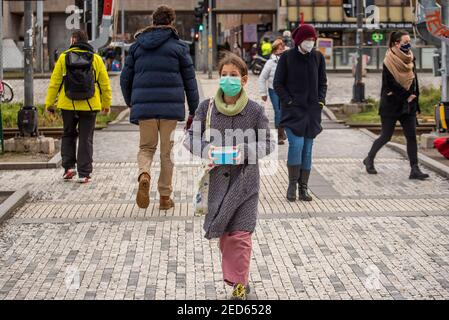 Prag, Tschechische Republik. 02-13-2021. Mädchen mit Maske überquert die Eisenbahn im Stadtzentrum von Prag während eines kalten Wintertages. Stockfoto