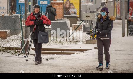 Prag, Tschechische Republik. 02-13-2021. Zwei Frauen tragen an einem kalten Wintertag im Zentrum von Prag die Ausrüstung des Himmels, während sie die Eisenbahn durchqueren. Stockfoto