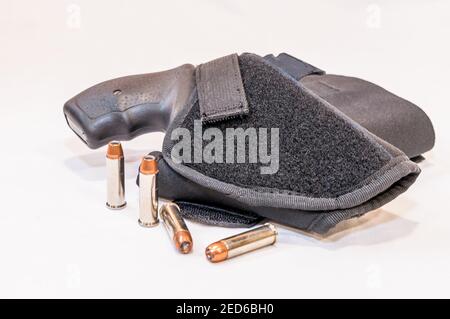 Ein schwarzer Schnupfnase 38 Spezialrevolver in einem Tuch Holster mit vier hohlen Punkt Kugeln daneben auf Ein weißer Hintergrund Stockfoto