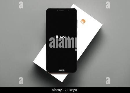 Huawei-Logo auf dem schwarzen Bildschirm des Smartphones auf der Oberseite Seine weiße Schachtel auf grauem Hintergrund Stockfoto