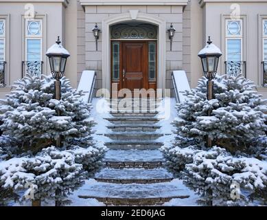 Elegante Holzmaserung Haustür des Hauses im Winter mit Schneebedeckte Kiefernbüsche Stockfoto