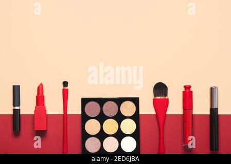 Verschiedene Make-up weibliche Kosmetik und Accessoires auf einem beige und Roter Hintergrund.Make-up Beauty Fashion Konzept Stockfoto