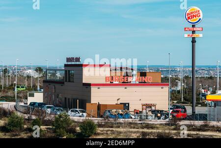 Vor dem Hotel befindet sich ein Fast-Food-Restaurant Burger King mit elegantem, zeitgemäßem, futuristischem Industrielook mit Ziegelsteinverkleidung und Drive-Thru-Bestellstelle Stockfoto