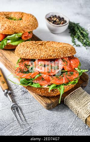 Geräucherter Lachs Bagels Sandwich mit Weichkäse und Rucola auf einem Schneidebrett. Weißer Hintergrund. Draufsicht Stockfoto
