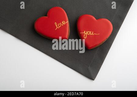 Zwei herzförmige Plätzchen mit roter Zuckerglasur auf grauem und weißem Hintergrund. Valentinstag Stockfoto