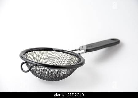 Nahaufnahme eines schwarzen Metallsiebs, auf weißem Hintergrund, horizontal, mit Kopierbereich Stockfoto