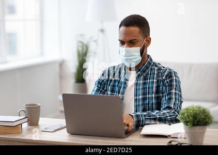 Afrikanischer Mann Am Laptop Trägt Schützende Gesichtsmaske Arbeitet Im Innen Stockfoto