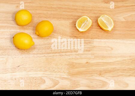 Ganze Zitronen und geschnittene Zitronen auf Holztisch, Holzboden Stockfoto