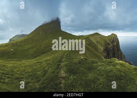 Kalsoy Insel mit Kallur Leuchtturm auf den Färöer Inseln, Dänemark, Europa. Wolken über hohen Klippen, türkisfarbenes Atlantisches Meer und spektakuläre Aussichten. Stockfoto