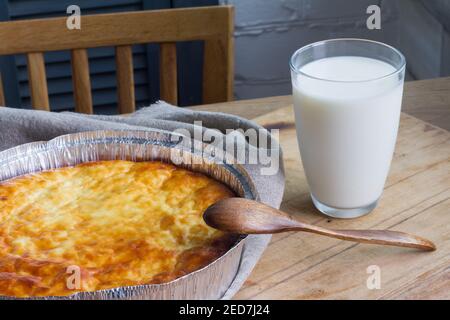Hüttenkäse Auflauf mit Tasse Milch auf Holztisch Hintergrund. Kasserolle mit Quark. Stockfoto