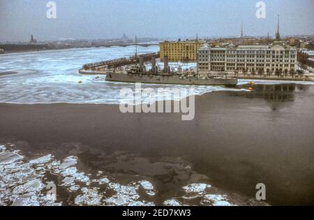 1990 Archivfoto des Cruiser Aurora über den gefrorenen Fluss Bolshaya Nevka und den Fluss Neva in Leningrad, jetzt St. Petersburg, Russland. Stockfoto