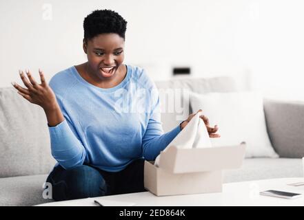 Frustriert schwarze Frau Auspacken falsche Box, Lieferfehler Stockfoto