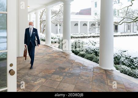 Eine Schneedecke bedeckt den Rosengarten des Weißen Hauses, während US-Präsident Joe Biden entlang der Kolonnade zum Oval Office am 1. Februar 2021 in Washington, D.C., spaziert. Stockfoto