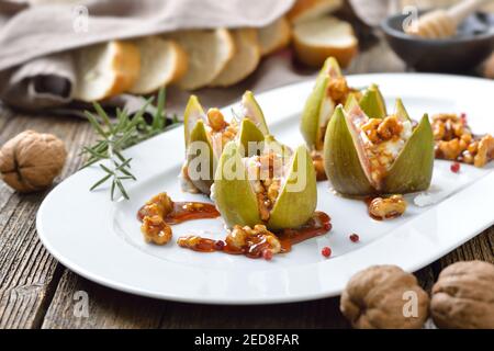 Gebackene Feigen gefüllt mit Ziegen Frischkäse und kandierten Walnüssen Mit süßem Honig und Rosmarin Stockfoto