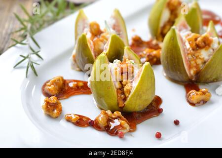 Gebackene Feigen gefüllt mit Ziegen Frischkäse und kandierten Walnüssen Mit süßem Honig und Rosmarin Stockfoto